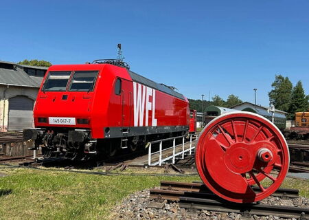 rote Elektrolokomotive steht auf Drehscheibe vor den Lokschuppen des Heimat Betriebswerk Nossen. Drehscheibe ist eine Einrichtung zum horizontalen Drehen von Schienenfahrzeugen zum Anschlussgleis.