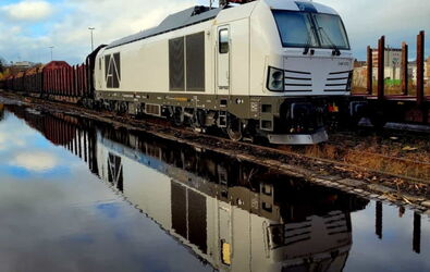 Eine weiße WFL-Lok-BR 248 Vectron Dual mit angehängten Güterwagen in Fahrt.