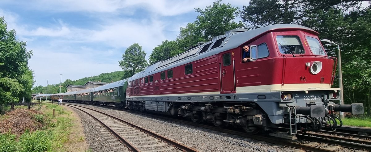 Sonderzug mit roter Diesellok fährt durch Landschaft