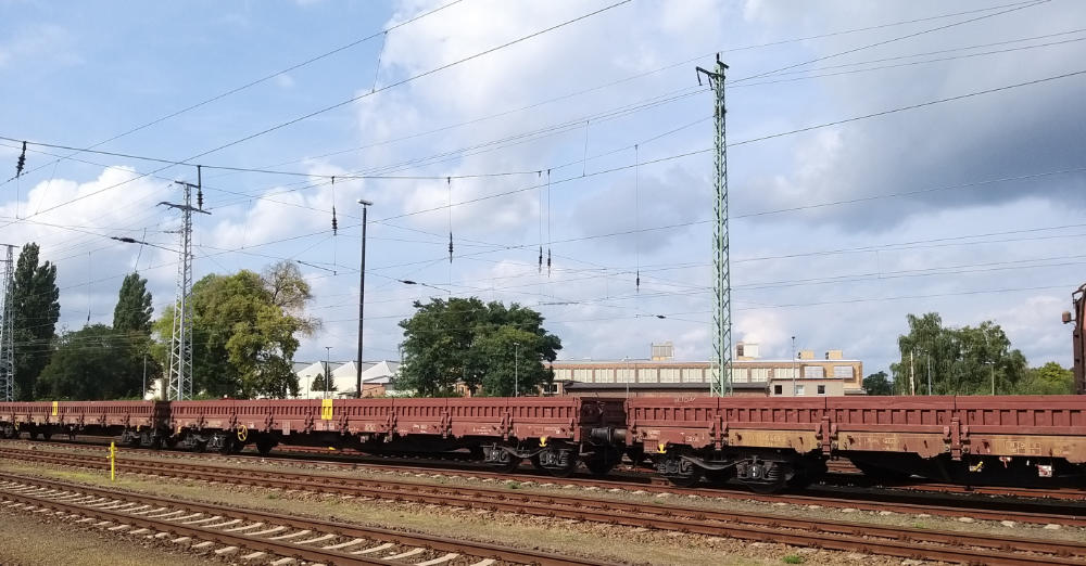 weinrote Güterwagen/Flachwagen mit geschlossenen Seitenklappen auf der Strecke